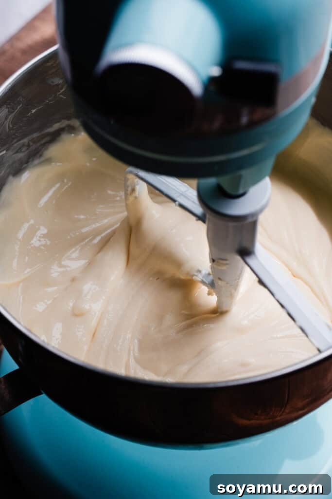Velvety Rich New York Cheesecake Masterpiece 10 The final silky smooth cheesecake batter resting in the bowl of a stand mixer, perfectly blended and ready for baking.