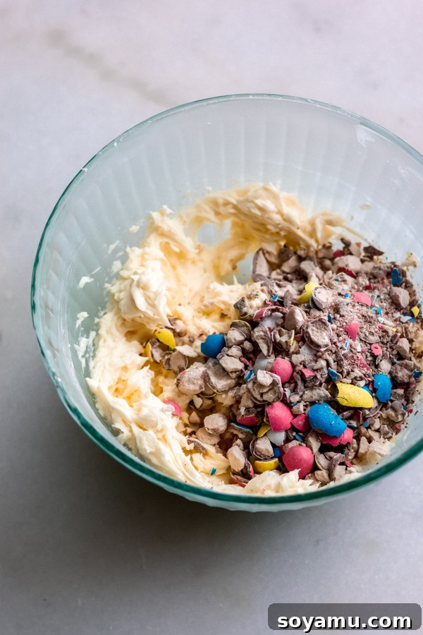 Robin's Egg Candy Frosting: Adding Crunch and Color to Easter Blondies A bowl of creamy, light blue frosting mixed with crushed Robin Egg candies, ready to be spread over Easter blondies.
