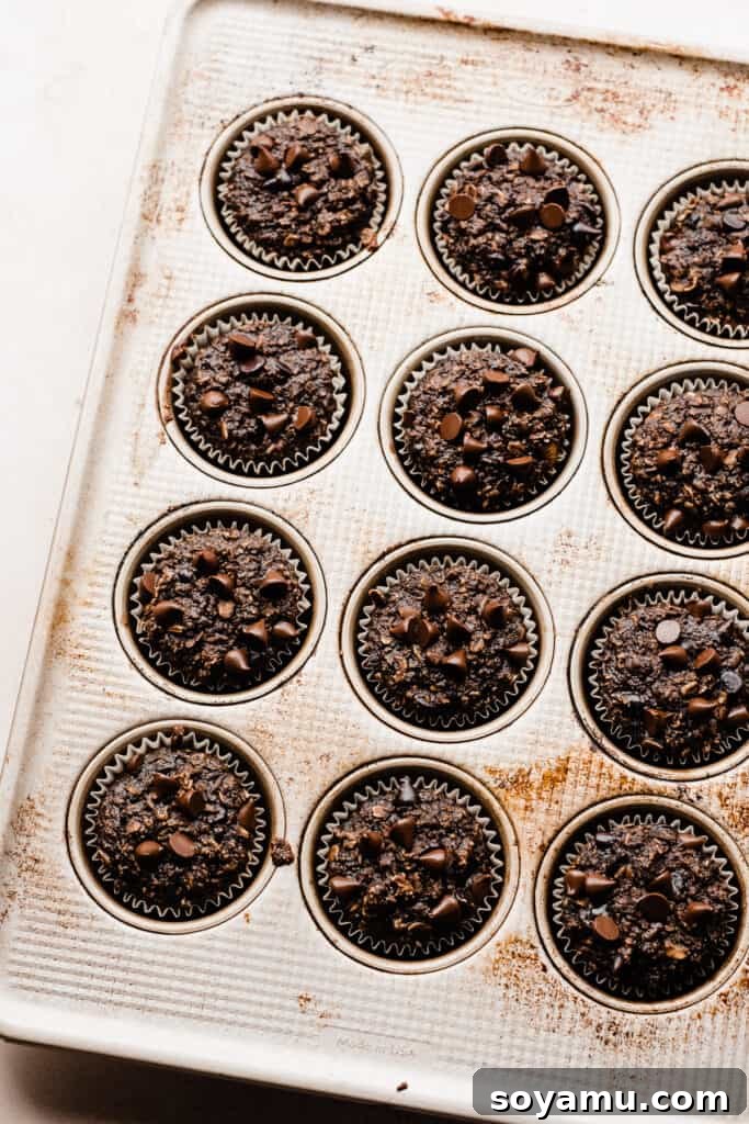 Wholesome Banana Chocolate Oat Muffins 7 A baking sheet filled with golden-brown, freshly baked banana chocolate oat muffins, straight from the oven.