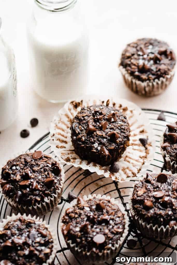 Wholesome Banana Chocolate Oat Muffins 8 Delicious banana chocolate oat muffins resting on a wire cooling rack, with glass bottles of milk in the background, suggesting a perfect pairing.