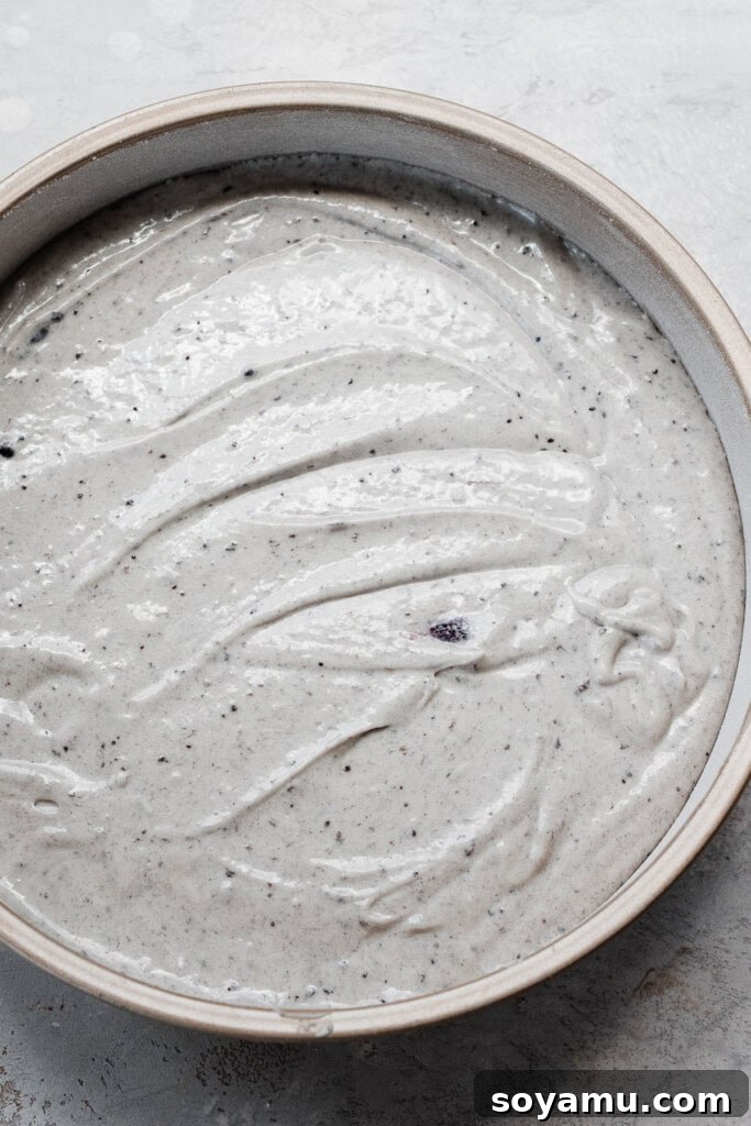 Blueberry Bliss Cake 12 Smooth, purple-tinted cake batter poured into a greased and floured cake pan, ready for baking.