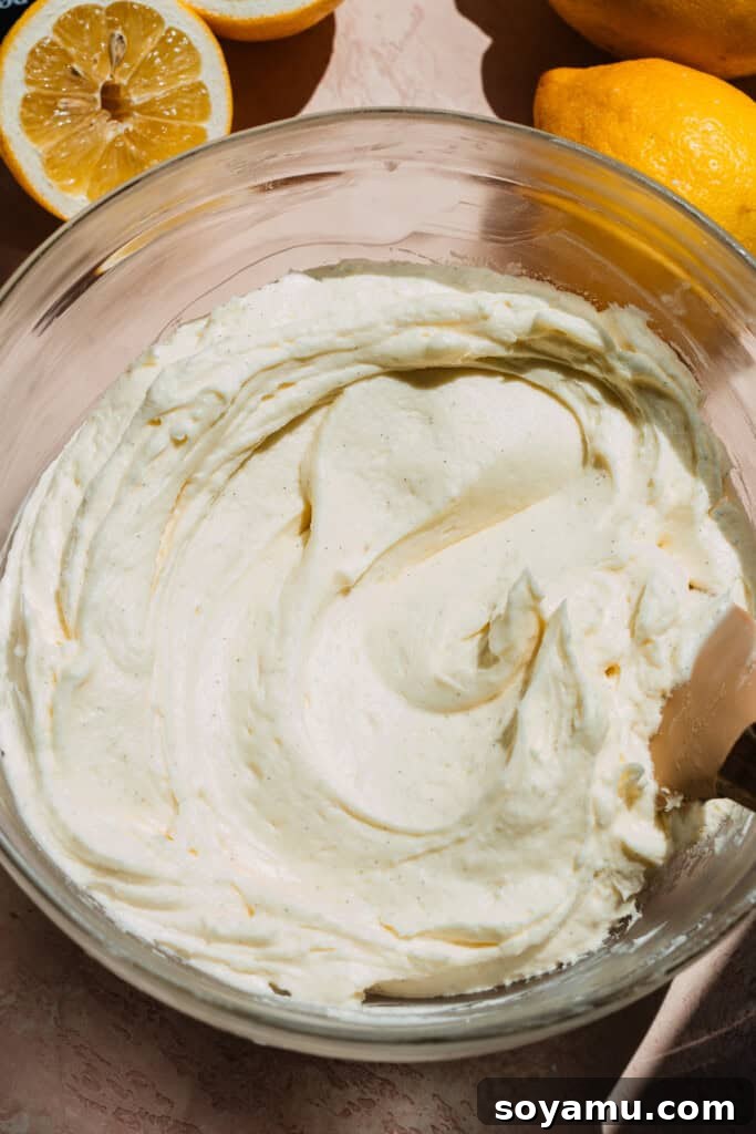 Velvet Lemon Mascarpone Cake 9 An offset spatula spreading the lemon mascarpone frosting smoothly over the cooled lemon cake.