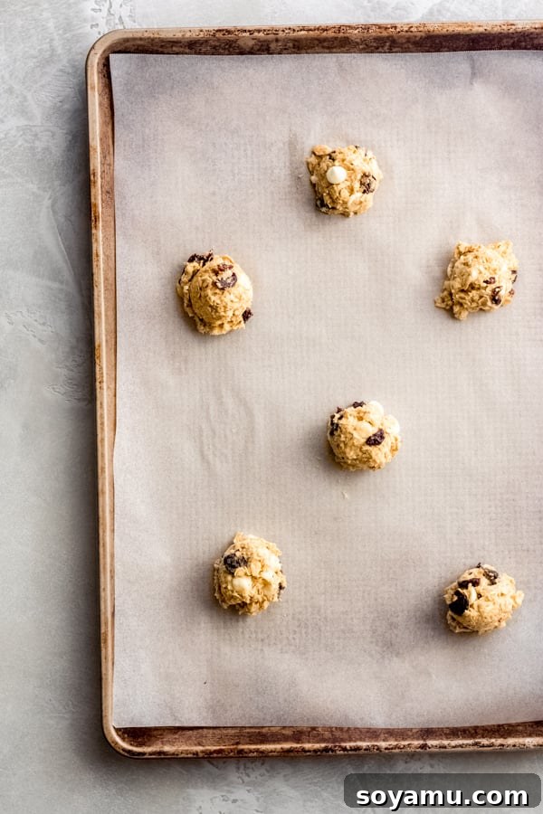 Luscious White Chocolate Cherry Oatmeal Cookies 5 Uniformly scooped white chocolate cherry oatmeal cookie dough balls arranged on a baking sheet.