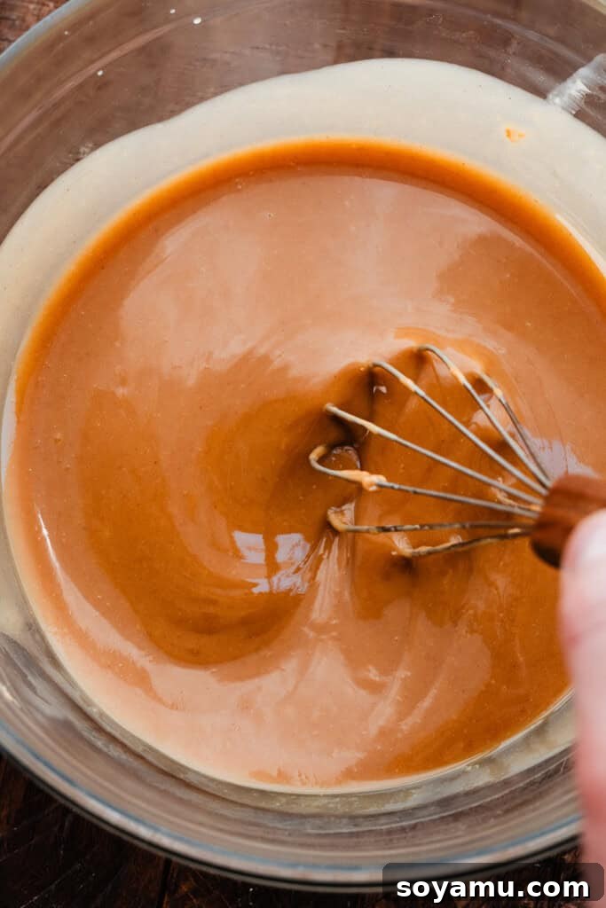 Chill-Free Peanut Butter Cookies 4 A bowl of melted butter and creamy peanut butter being whisked together until smooth and fully combined.