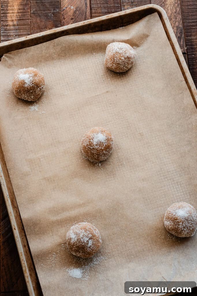 Chill-Free Peanut Butter Cookies 6 Perfectly portioned cookie dough balls, coated in granulated sugar, neatly arranged on a baking sheet, ready for the oven.
