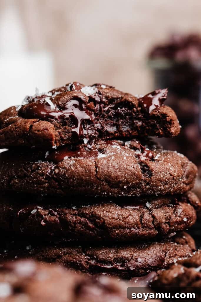Decadent Double Chocolate Chip Cookies 2 A stack of perfectly baked double chocolate chip cookies, with a delectable bite missing from the top cookie, revealing its rich, fudgy interior and melted chocolate chips.