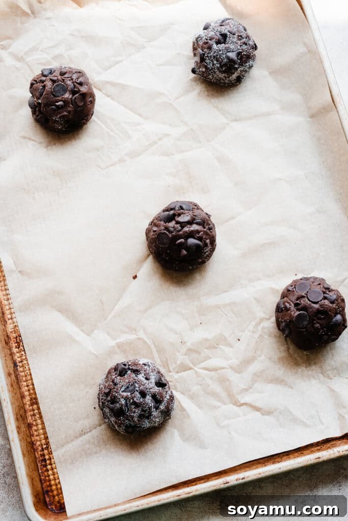 Decadent Double Chocolate Chip Cookies 6 A baking sheet with precisely arranged double chocolate chip cookie dough balls, spaced out for optimal baking.