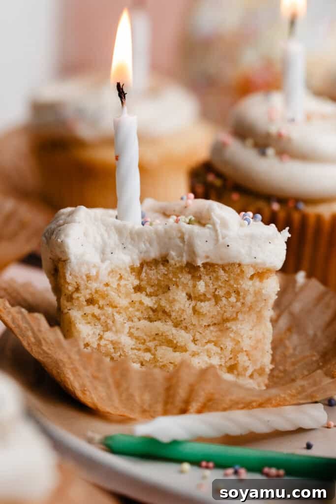 A vanilla cupcake with a few bites missing, revealing its incredibly light, airy, and fluffy texture inside, inviting a taste.