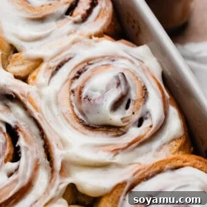 A close-up of a frosted cinnamon roll in a baking dish, showcasing its irresistible appeal.