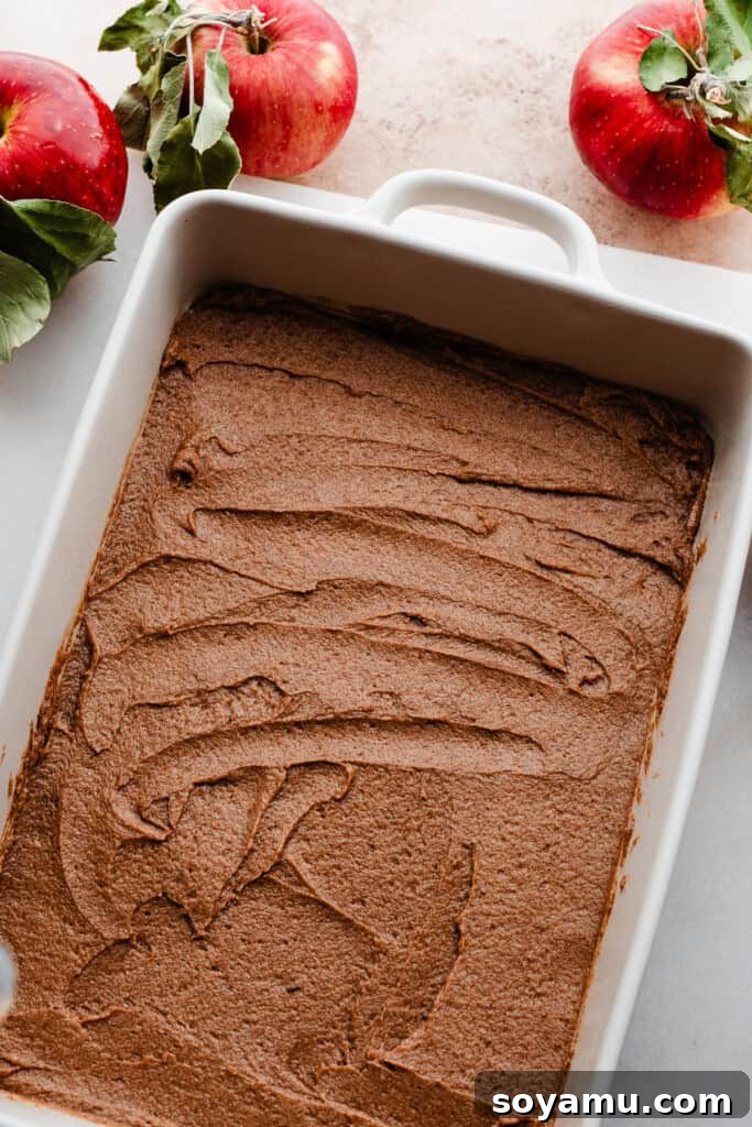 The cinnamon caramel sauce evenly spread across the bottom of a baking dish, awaiting the rolls.
