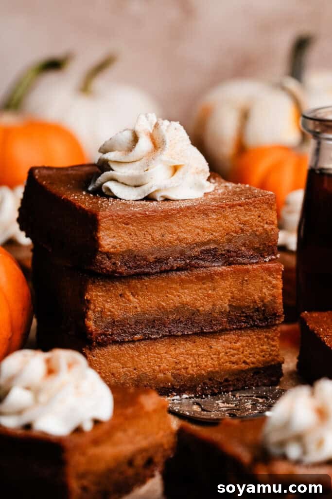 Perfectly Simple Pumpkin Pie Bars 2 A stack of three pumpkin pie bars, topped with a swirl of whipped cream, invitingly presented.