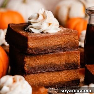A stack of pumpkin pie bars, topped with a swirl of whipped cream, making a delicious dessert.