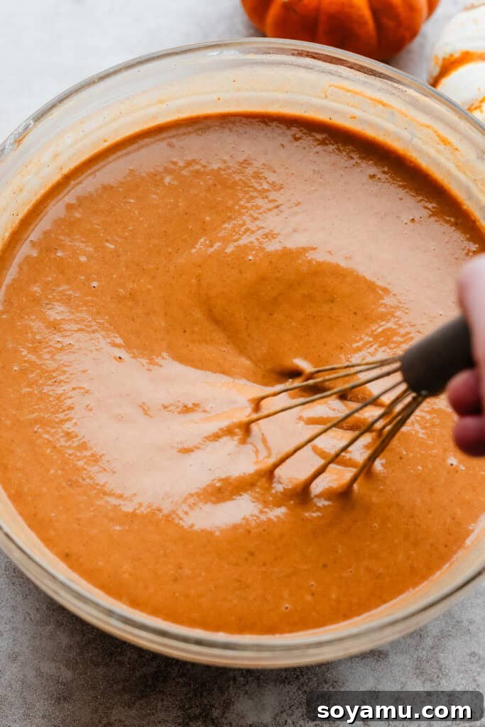 Autumn's Best Pumpkin Pie 7 A bowl of creamy pumpkin pie filling being whisked to perfection, showcasing its smooth texture and rich color.