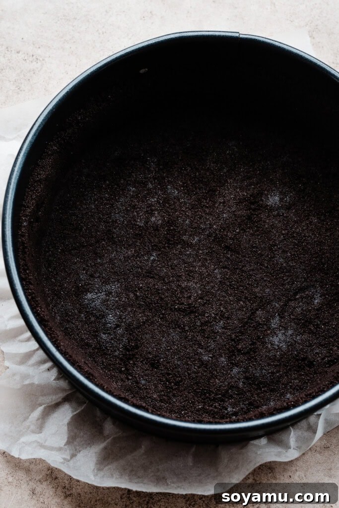 Simple Two Ingredient Oreo Dessert Crust 8 A pristine Oreo crust, tightly packed into a 9-inch springform pan, awaiting baking and the creamy cheesecake filling for a perfect dessert.