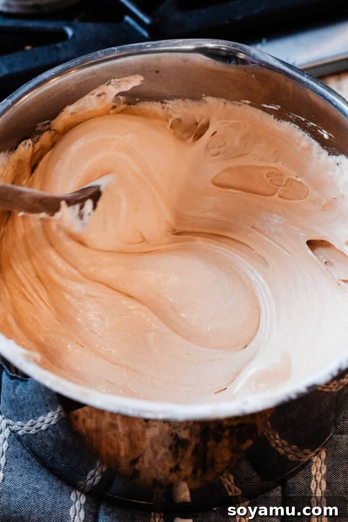 The hot peanut butter fudge mixture being vigorously stirred in the pot after removal from heat, showing the ingredients blending.