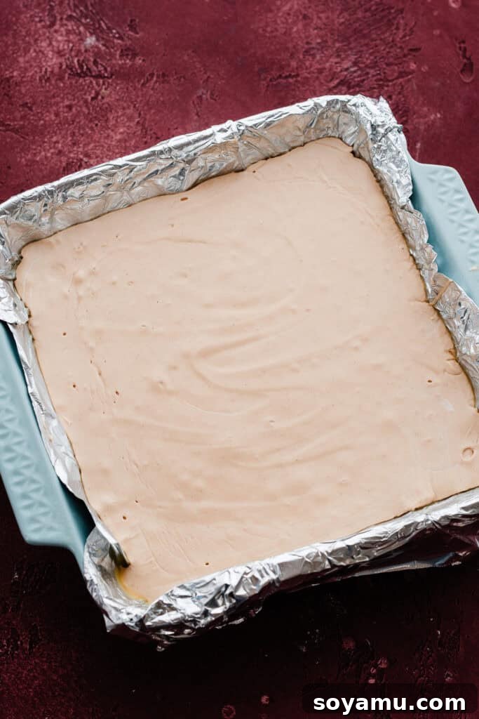 The chilled and perfectly set peanut butter fudge in the pan, ready to be lifted out and sliced into squares.