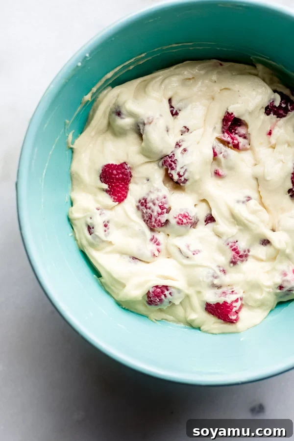 One Bowl Raspberry Lemon Bread - This quick bread is filled with spring flavor in the form of raspberries and lemon, it requires only one bowl and can be dressed up with a 2-ingredient glaze. It's flavorful, moist, and is begging to be baked immediately! #raspberrylemon #onebowlrecipe #quickbread #lemonbread #poundcake #lemoncake #springrecipes #springdesserts #dessertrecipes #bluebowlrecipes | bluebowlrecipes.com Bread batter in a bowl with fresh raspberries gently folded in, ready for baking.