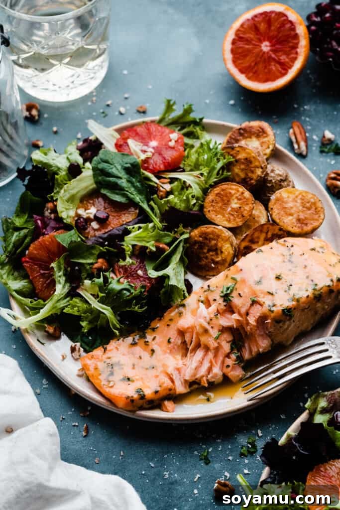 Sheet Pan Caramelized Maple Salmon with Crispy Potatoes 3 A plate of flaky salmon with a fork digging in.