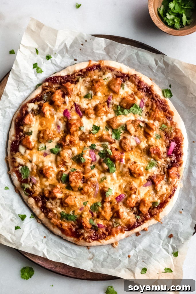 Our Favorite Barbecue Chicken Pizza - Pizza night just got even more delicious! An easy homemade crust is the base for this pizza made with chicken, barbecue sauce, mozzarella and colby jack cheese, green pepper, and red onion. This is what every weekend (and weeknight!) calls for! #barbecuechicken #chicken #pizza #barbecuechickenpizza #bbq #bbqchicken #homemadepizza #weeknightdinner #easydinner | bluebowlreicpes.com A freshly baked barbecue chicken pizza on a rustic wooden board.