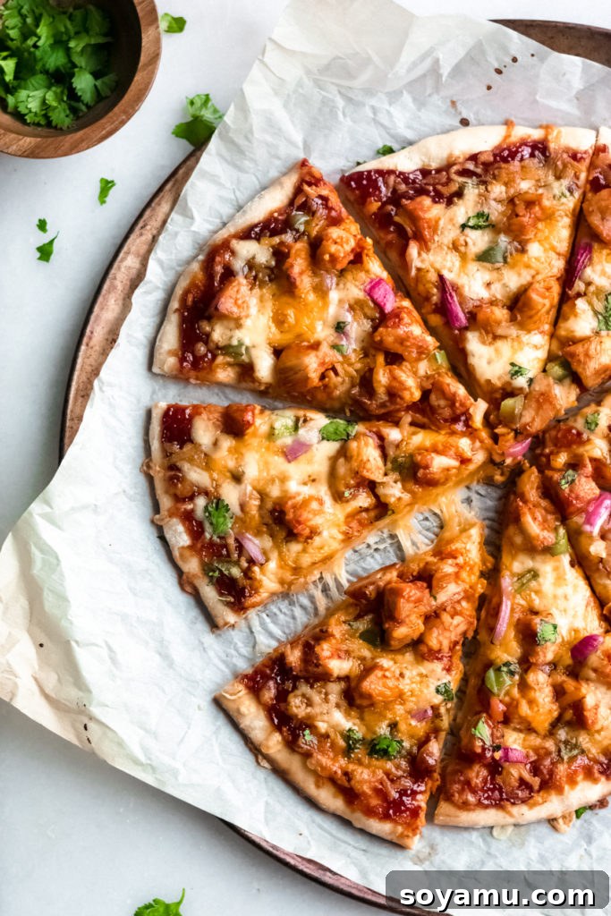 Our Favorite Barbecue Chicken Pizza - Pizza night just got even more delicious! An easy homemade crust is the base for this pizza made with chicken, barbecue sauce, mozzarella and colby jack cheese, green pepper, and red onion. This is what every weekend (and weeknight!) calls for! #barbecuechicken #chicken #pizza #barbecuechickenpizza #bbq #bbqchicken #homemadepizza #weeknightdinner #easydinner | bluebowlreicpes.com Multiple enticing slices of BBQ chicken pizza, garnished with fresh cilantro.
