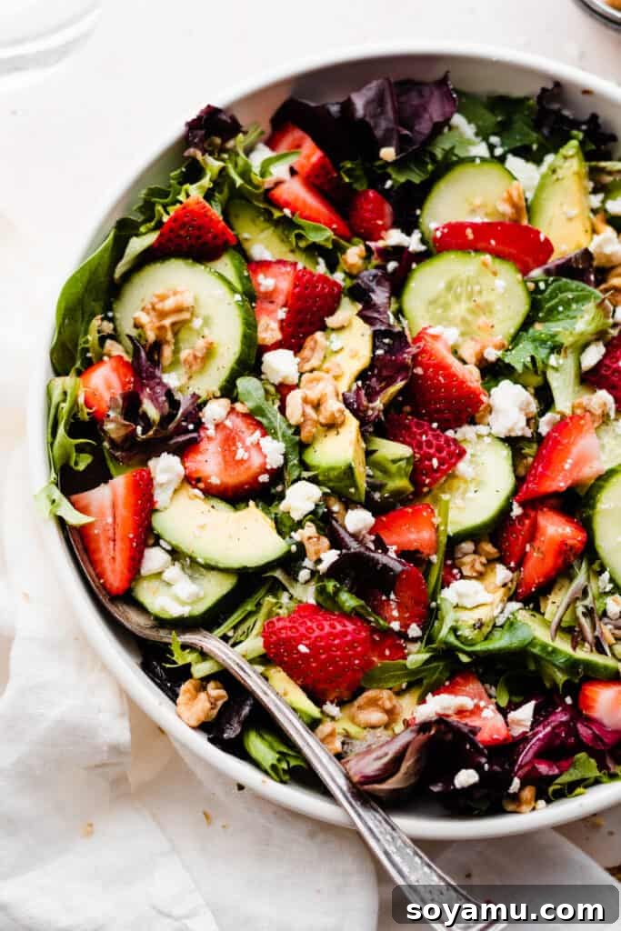 Vibrant Strawberry Cucumber Salad with Goat Cheese and Toasted Walnuts 4 A close-up of the tossed salad in a serving bowl.