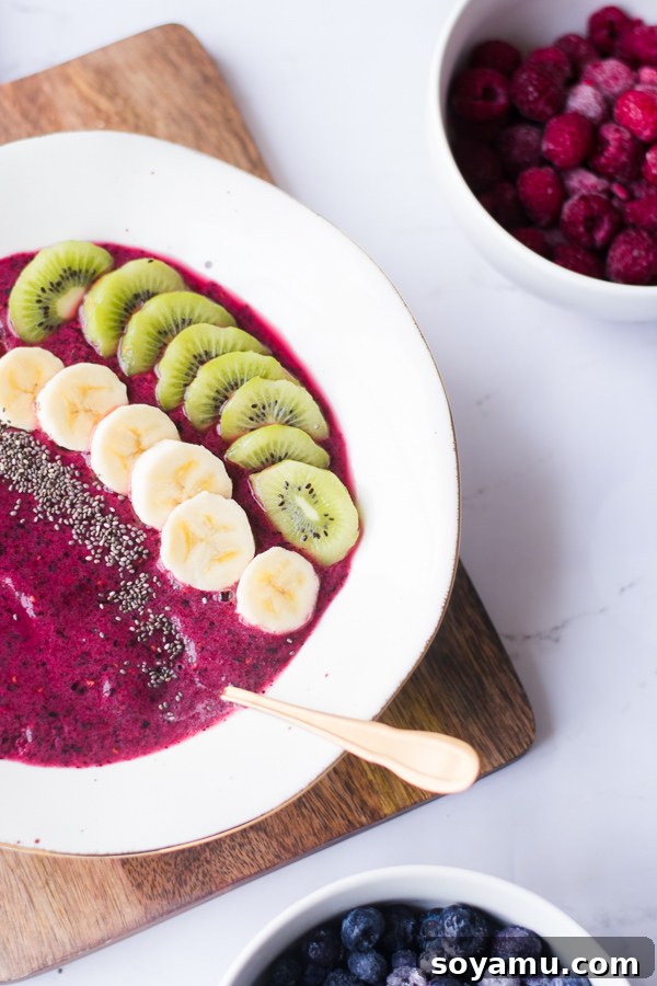 Smoothie bowl topped with fruit and seeds, ready to be eaten