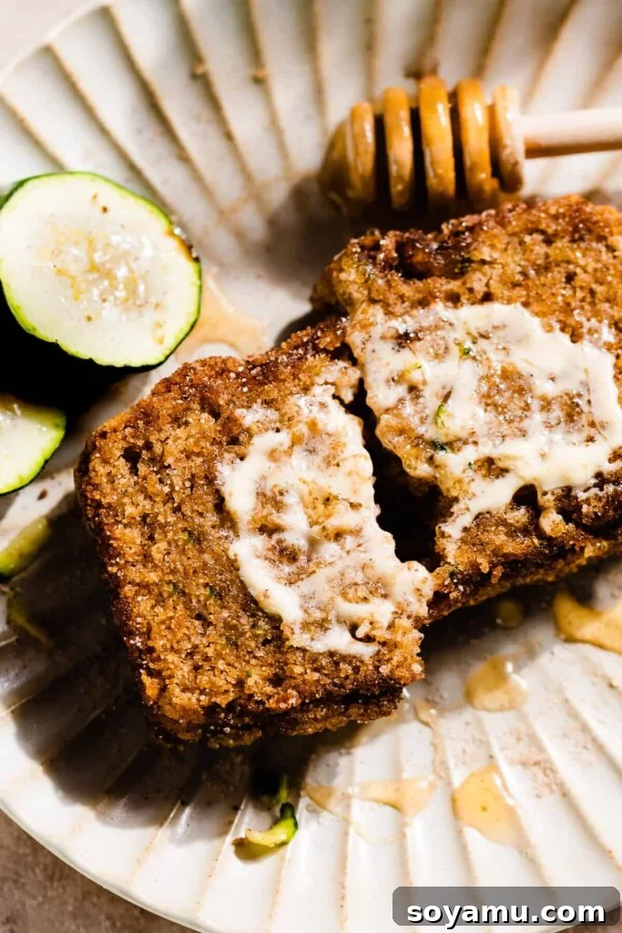 A close-up on a two halves of a slice of zucchini bread on a plate.