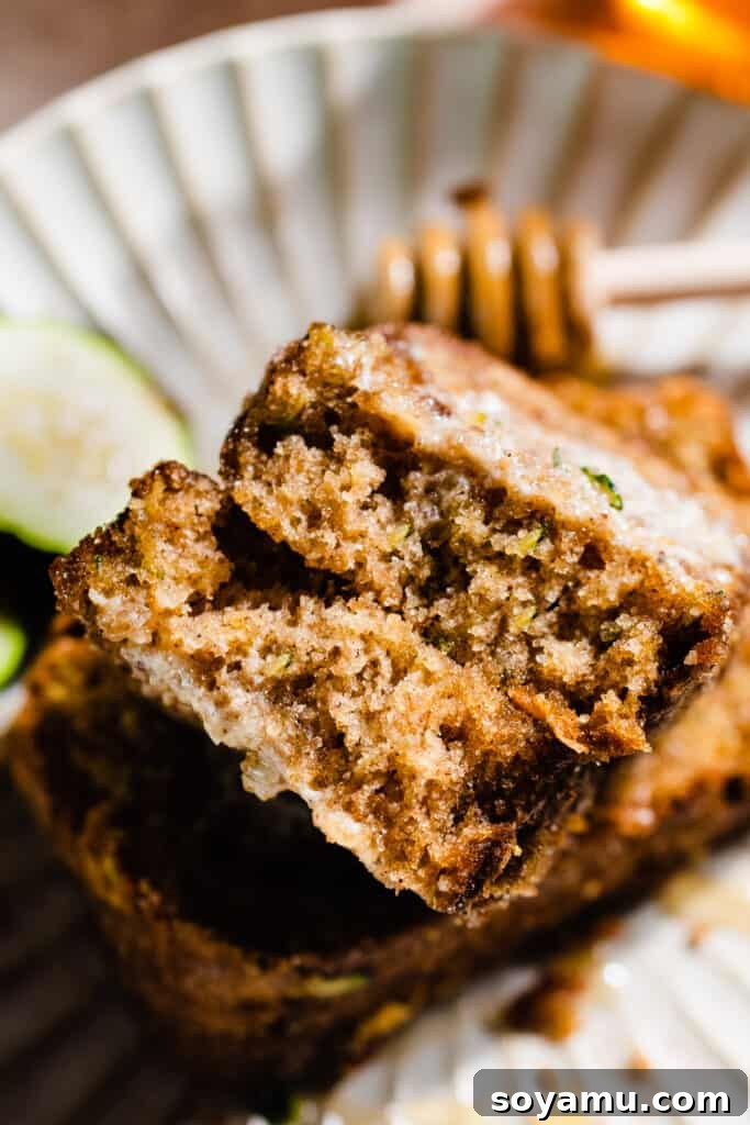 A slice of zucchini bread broken in half to show the fluffy interior.