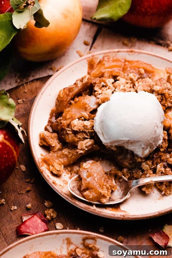 A plate of this dessert, topped with ice cream, with a spoon taking a bite.