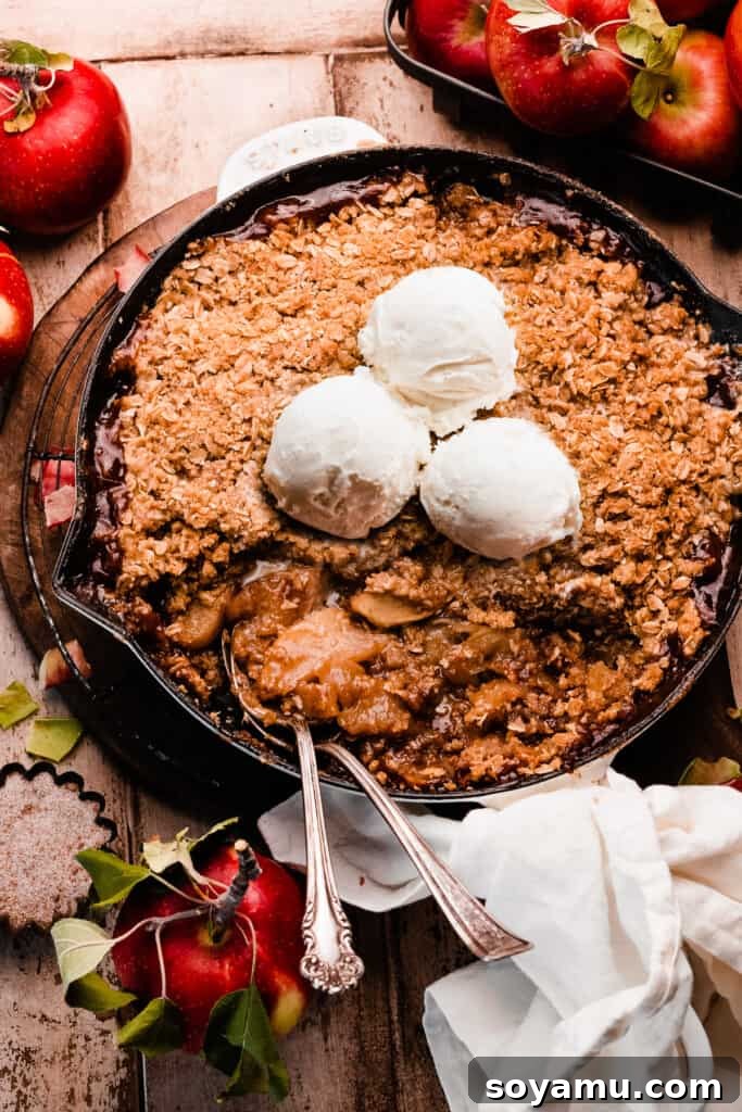 A skillet of apple crisp with serving spoons digging in.