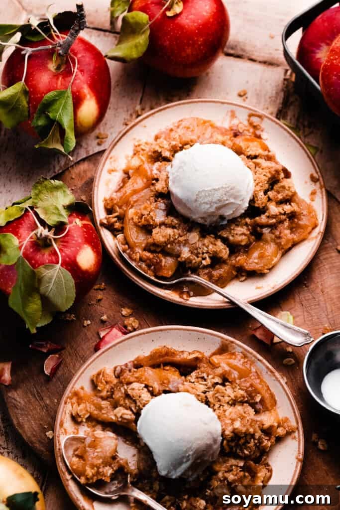 Two plates of apple crisp on a wooden serving board.