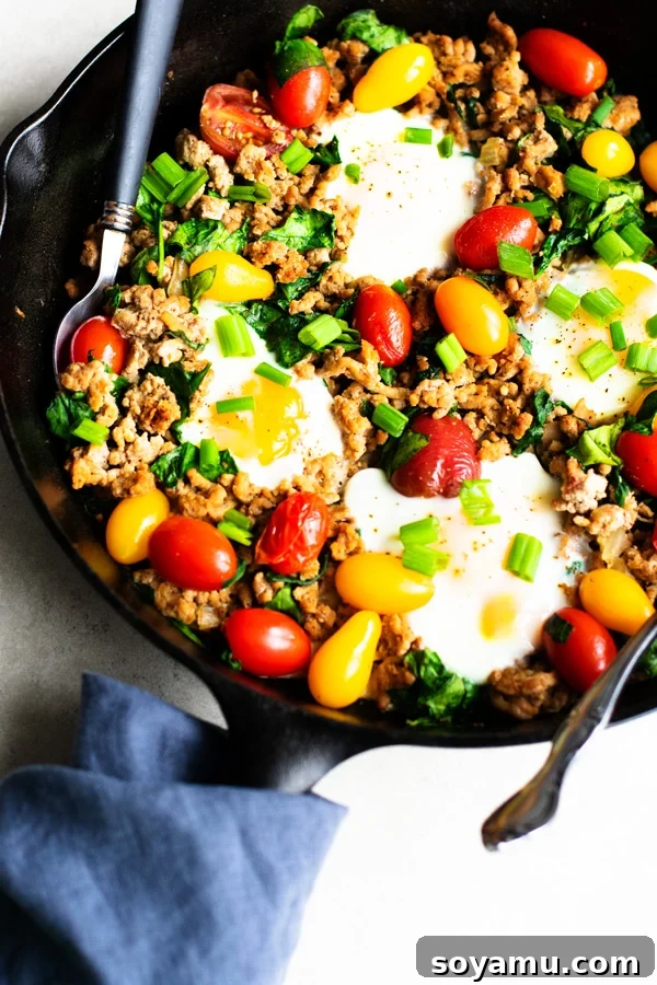 Healthy Taco Skillet baking in the oven with eggs visibly setting and tomatoes blistering