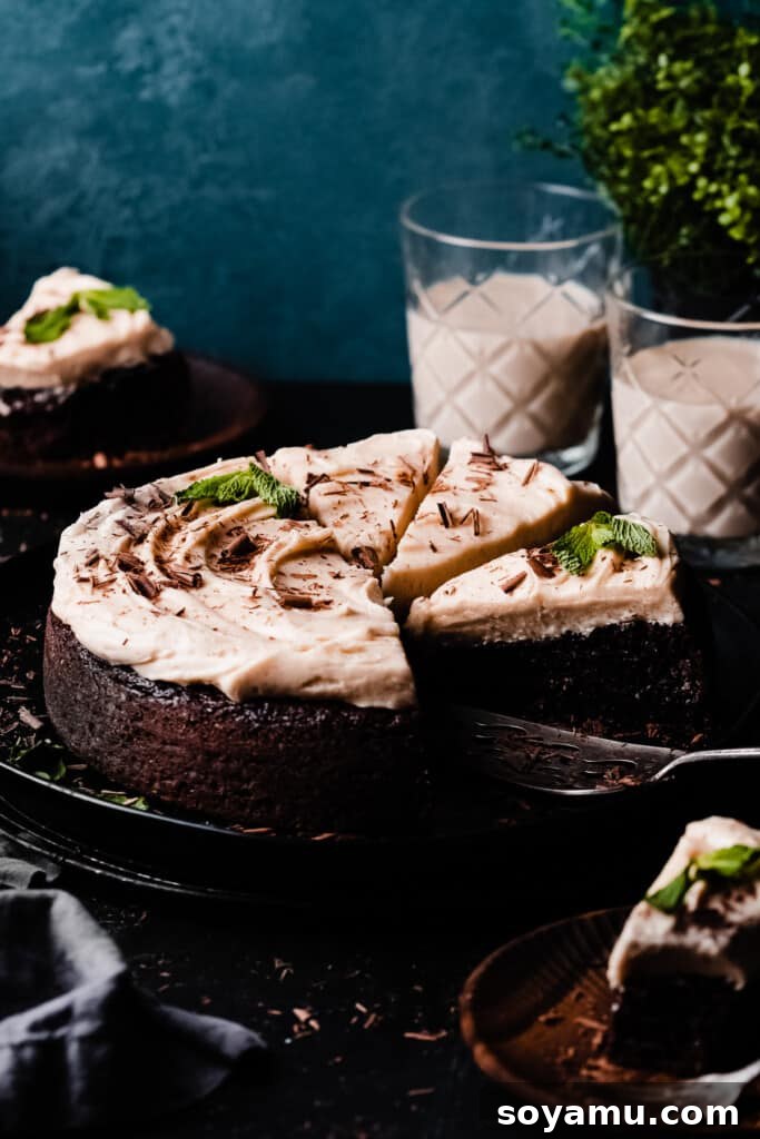 Decadent Baileys Chocolate Cake with Silky Cream Cheese Frosting 3 The sliced baileys cake on a cake plate, with chocolate shavings and mint leaves for garnish.