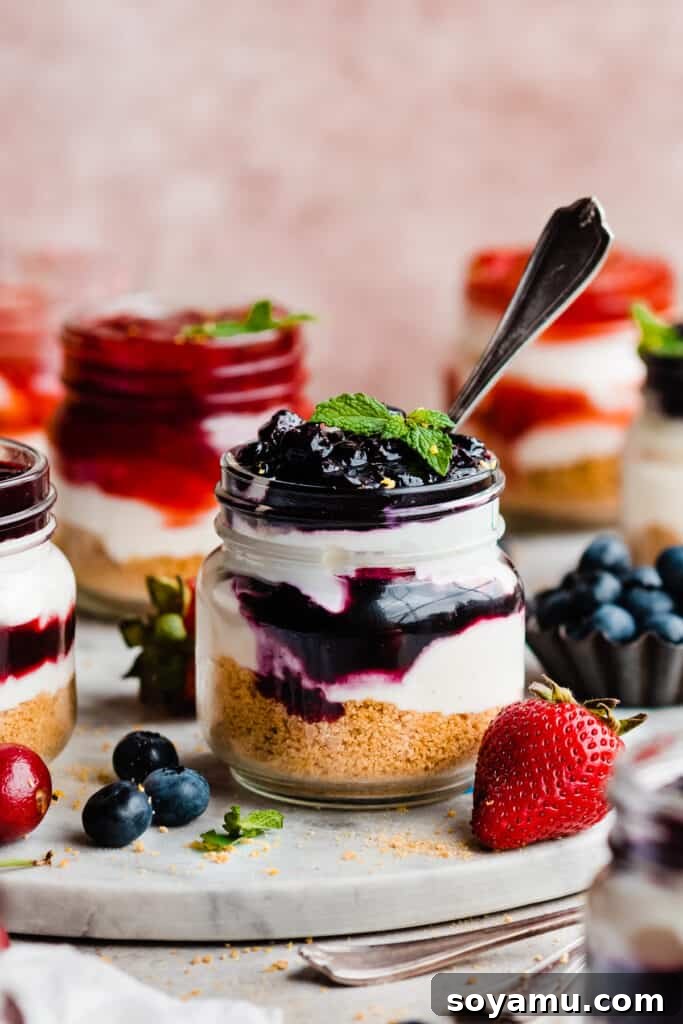 No-Bake Mini Cheesecake Jars 9 A jar of no-bake cheesecake topped with blueberry pie filling.