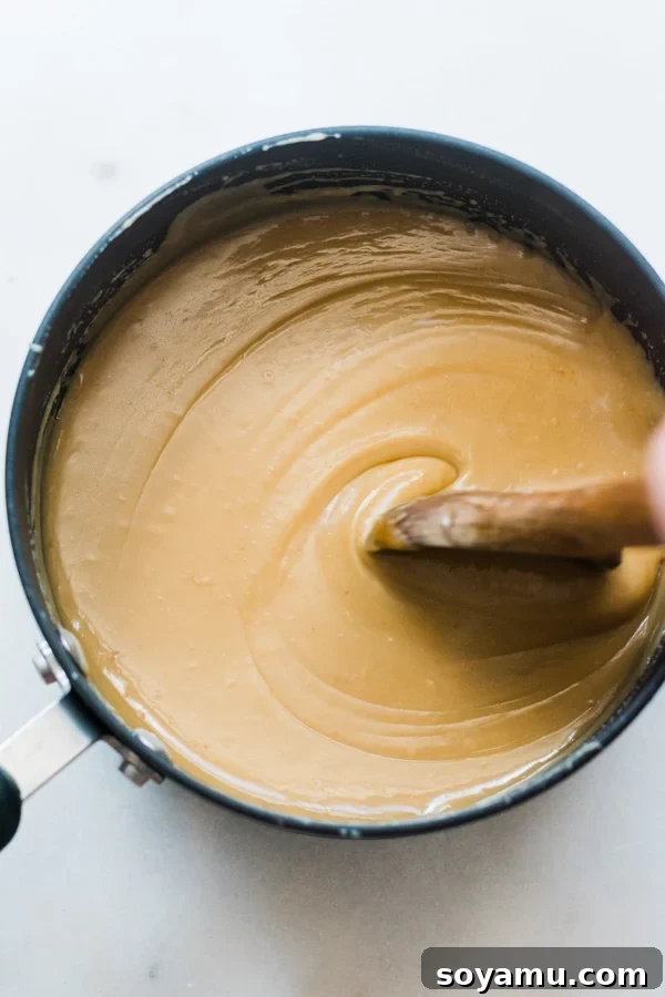 A pot of simple homemade caramel sauce, perfect for filling fudgy chocolate cookies or as a delightful coffee creamer. Pot of rich, homemade caramel sauce ready for baking or drizzling.