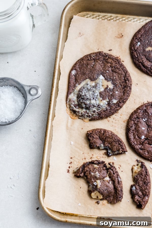 Close-up of a freshly baked caramel-stuffed chocolate cookie, with a hint of gooey caramel peeking out. A perfectly baked Caramel-Stuffed Chocolate Cookie, showcasing its gooey center and crisp edges.