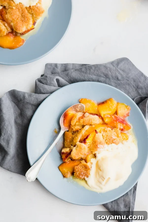 Individual Serving of Peach Cobbler Another perspective of a single serving of peach cobbler and vanilla ice cream on a plate, highlighting its comforting appeal.