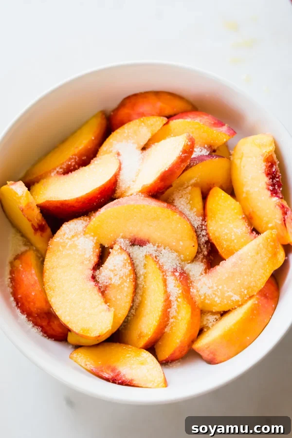 Peach Crisp Yogurt Parfaits 5 Sliced peaches being tossed with sugar in a bowl, preparing them for roasting.