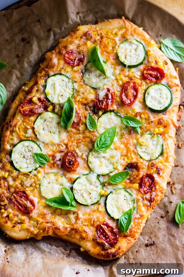 Delicious Roasted Tomato, Corn, and Zucchini Flatbread Pizza slices on a wooden board, garnished with fresh basil.