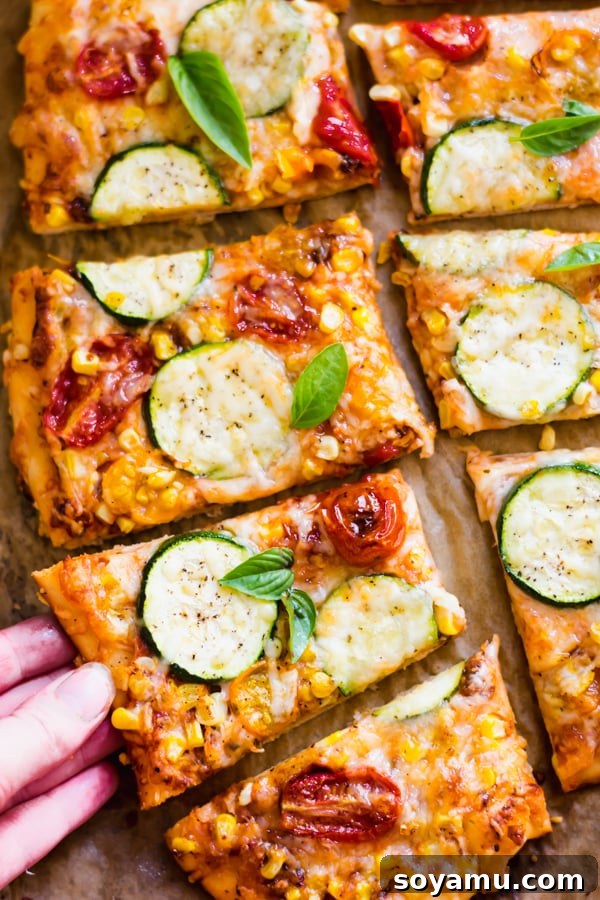 Two slices of freshly baked Roasted Tomato, Corn, and Zucchini Flatbread Pizza on a plate.