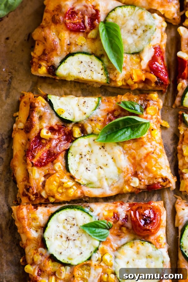 Close-up of freshly baked slices of Roasted Tomato, Corn, and Zucchini Flatbread Pizza, showcasing melted cheese and vibrant vegetables.