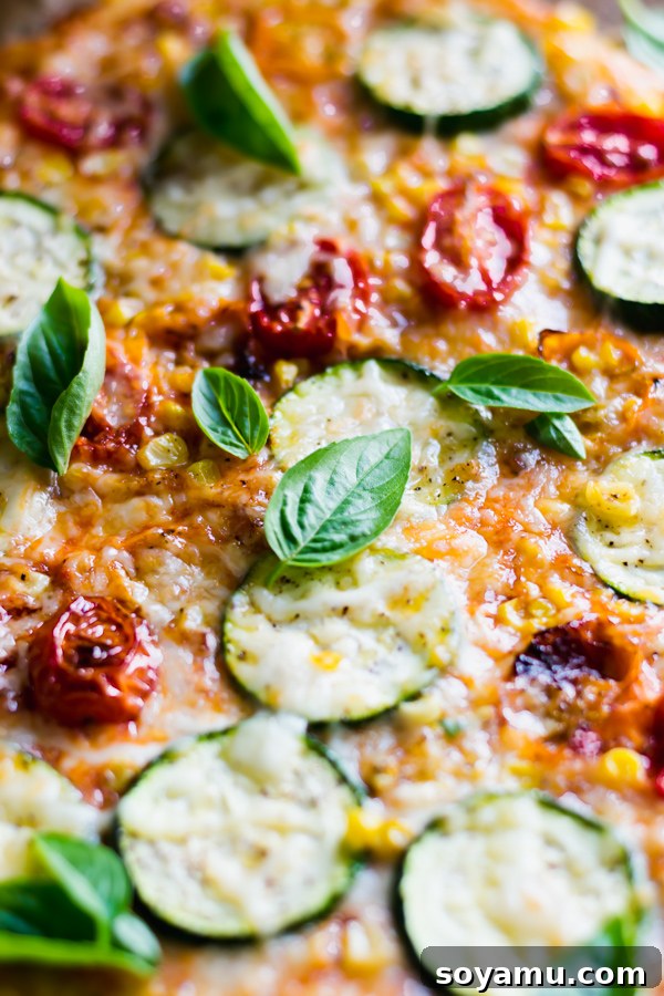 Close-up of a freshly baked Roasted Tomato, Corn, and Zucchini Flatbread Pizza, garnished with fresh basil.