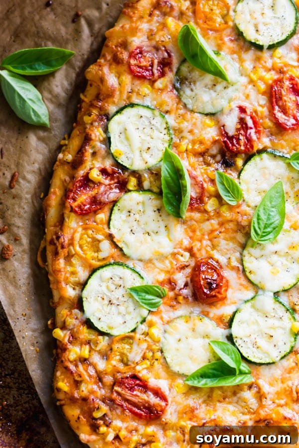 Close-up of a rustic-style slice of Roasted Tomato, Corn, and Zucchini Flatbread Pizza.