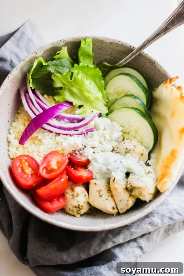 Savory Chicken Gyro Bowls with Artisan Tzatziki 2 A beautifully arranged chicken gyro bowl with lemon-herb chicken, couscous, fresh greens, cherry tomatoes, crumbled feta, thinly sliced red onions, and cucumber slices.