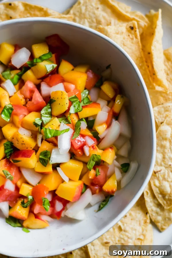 A bowl of peach salsa with tortilla chips on the side, ready to be enjoyed.