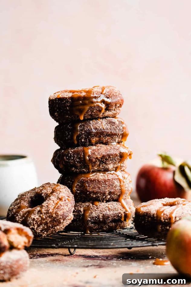 Ultimate Baked Apple Cider Donuts 2 A stack of apple cider donuts coated in apple pie spiced sugar and drizzled with salted caramel sauce.