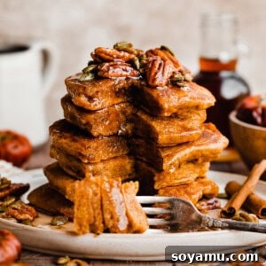 Pillowy Pumpkin Spice Pancakes 11 A tall stack of pumpkin pancakes topped with candied pecans and real maple syrup.