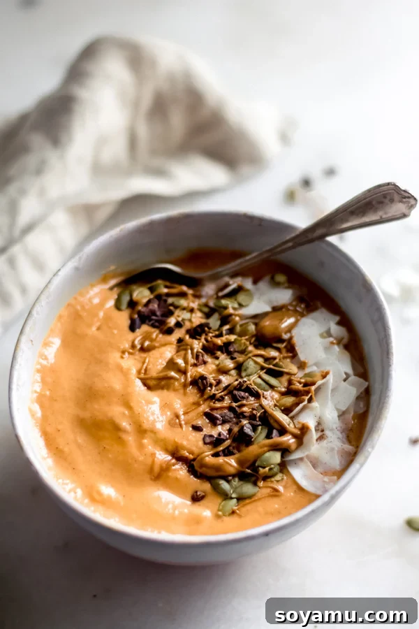 Fall Glow Smoothie Bowl - A delicious, creamy smoothie made with real food ingredients and lots of fall flavor. All you need for this filling breakfast is 6 ingredients and 10 minutes! #bluebowlrecipes #fall #smoothie #smoothiebowl #sweetpotato #dairyfree #vegan #glutenfree #breakfast #healthybreakfast | bluebowlrecipes.com A vibrant Fall Glow Smoothie Bowl adorned with coconut chips, cacao nibs, and pumpkin seeds, ready to be enjoyed.