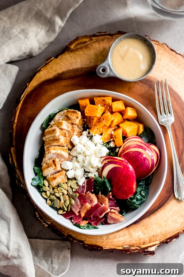 Fall Harvest Salad with Maple Tahini Dressing - A delicious salad filled with fall flavors and good-for-you ingredients like roasted butternut squash, honeycrisp apples, chicken, kale, and pumpkin seeds. No sad salads here! #butternutsquash #salad #fall #fallrecipes #mealprep #healthyrecipes #healthyfood #chicken #glutenfree | bluebowlrecipes.com A vibrant bowl of Fall Harvest Salad with Maple Tahini Dressing, featuring roasted butternut squash, apples, kale, chicken, bacon, and feta.