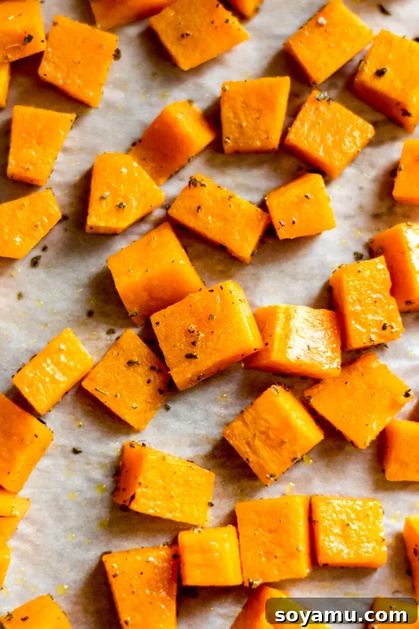 Fall Harvest Salad with Maple Tahini Dressing - A delicious salad filled with fall flavors and good-for-you ingredients like roasted butternut squash, honeycrisp apples, chicken, kale, and pumpkin seeds. No sad salads here! #butternutsquash #salad #fall #fallrecipes #mealprep #healthyrecipes #healthyfood #chicken #glutenfree | bluebowlrecipes.com Golden brown roasted butternut squash cubes perfectly caramelized on a baking sheet, showcasing autumn's bounty.